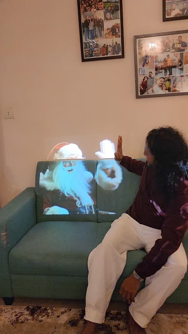 Santa Claus projected onto a green sofa, Srix reaching out to it