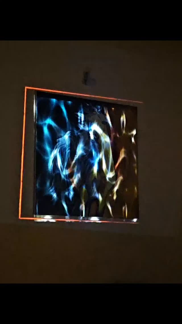 A square of generative blue light framed in orange on a dark wall