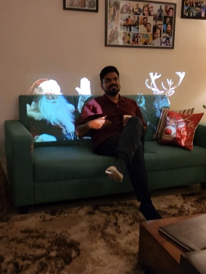 Srix sitting on a sofa lit with projected Santa and reindeer